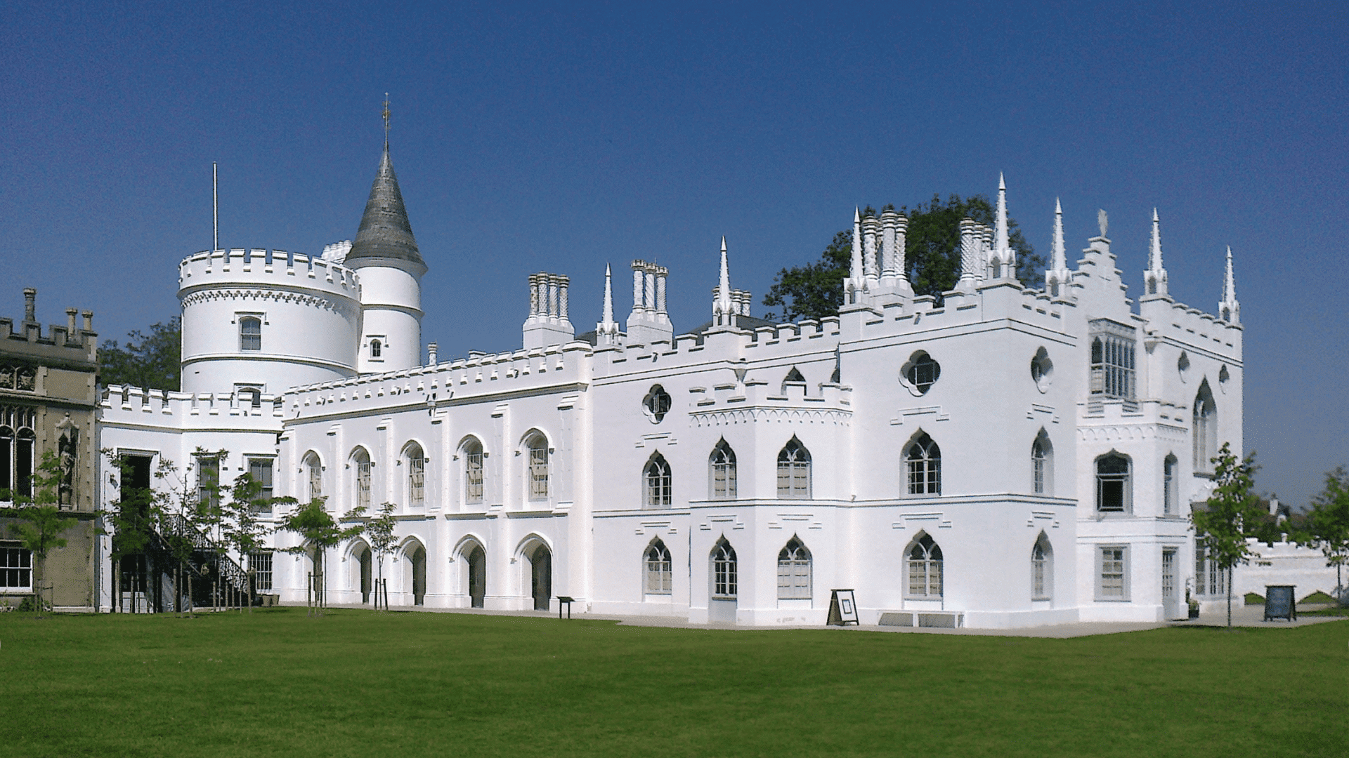A large white building, Strawberry Hill House in Twickenham, displays Gothic architecture with pointed arches and decorative elements.