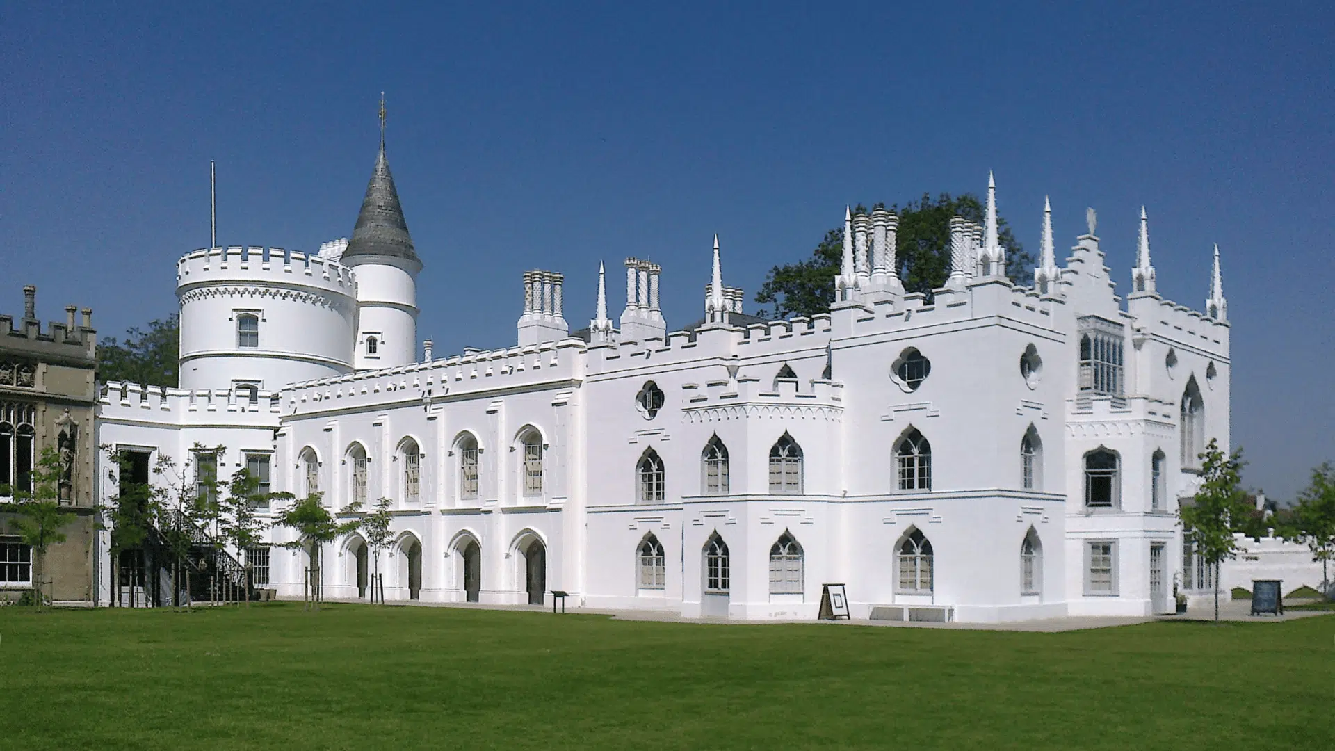 A large white building, Strawberry Hill House in Twickenham, displays Gothic architecture with pointed arches and decorative elements.