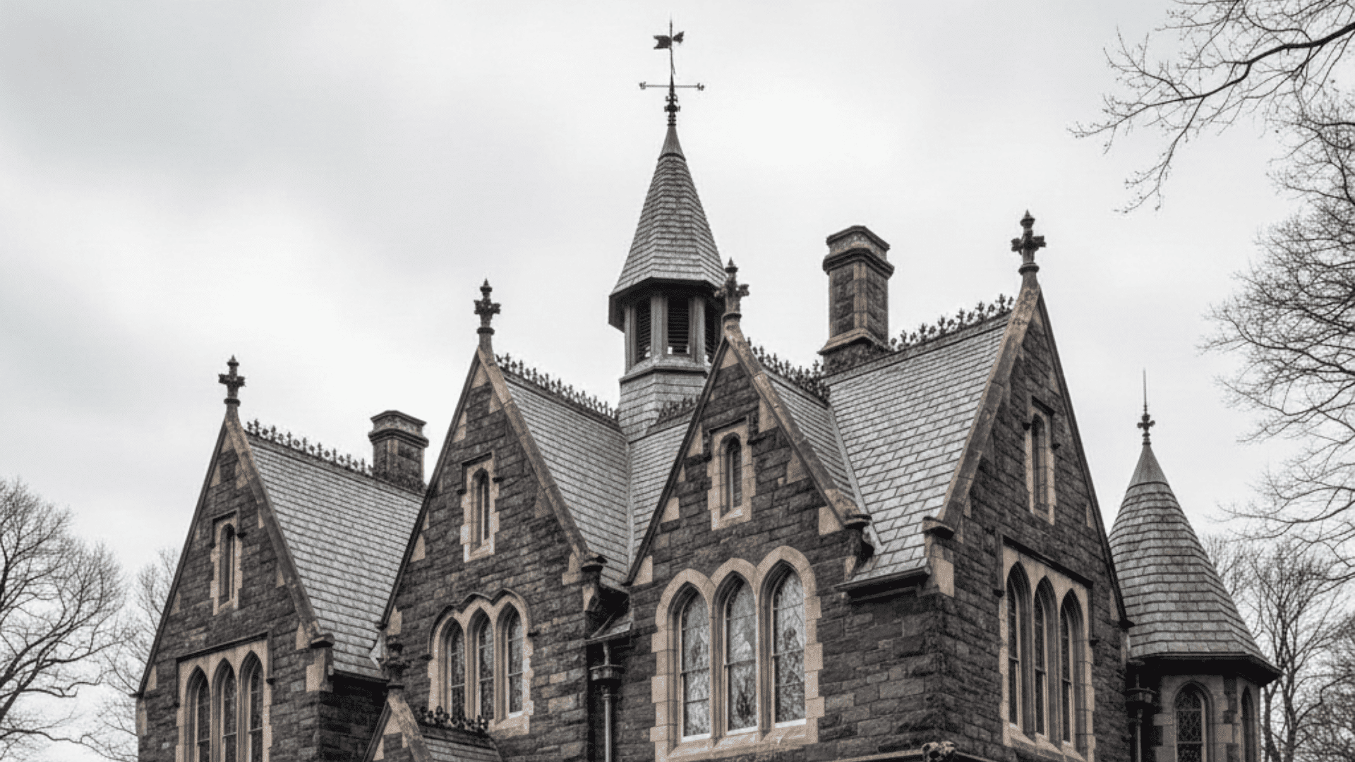 _Black and white photo of a large gothic building featuring steeply pitched roofs and intricate architectural details