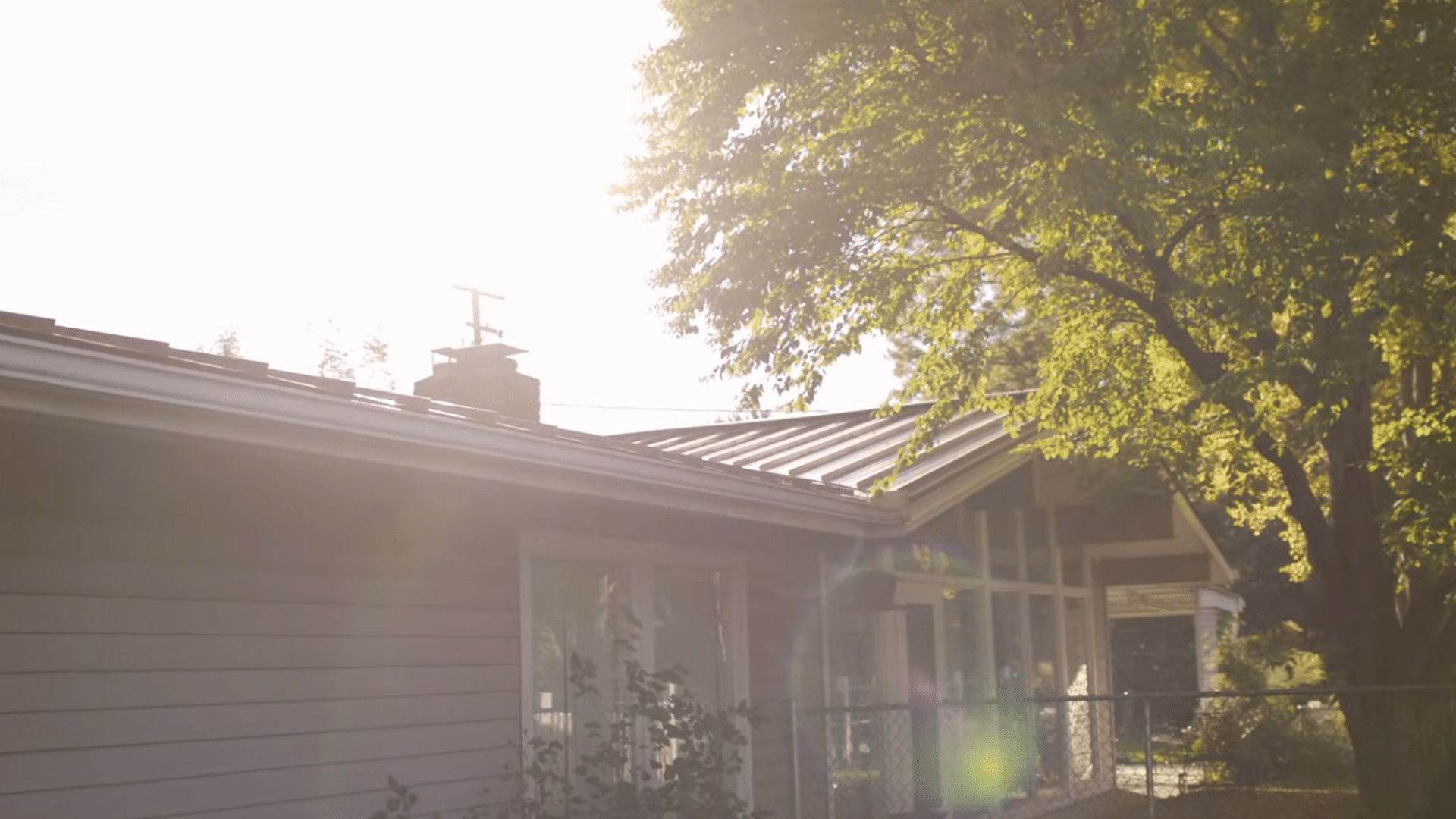 Metal roof on residential home under clear, sunny skies, showing ideal dry weather conditions for painting