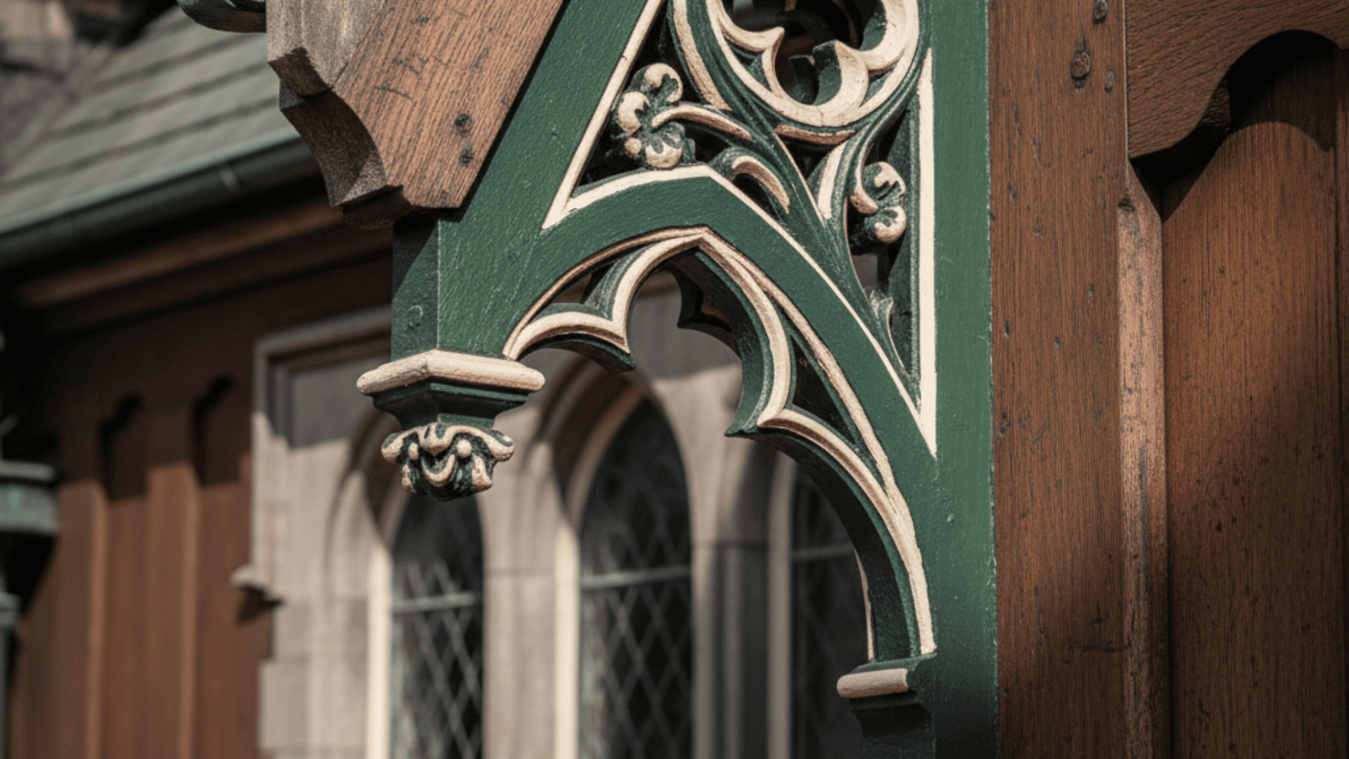_a green and white design mounted on a gothic architecture building with decorative bargeboard.