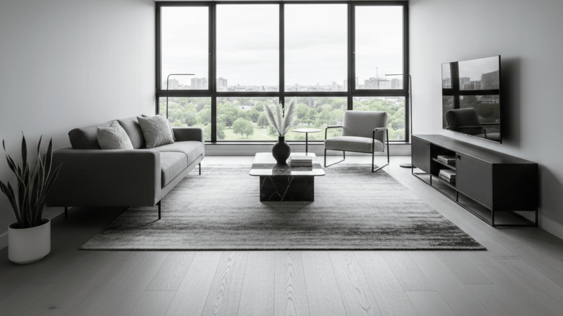 A modern living room featuring a couch, coffee table, and television, with ash floors and cool grey walls.
