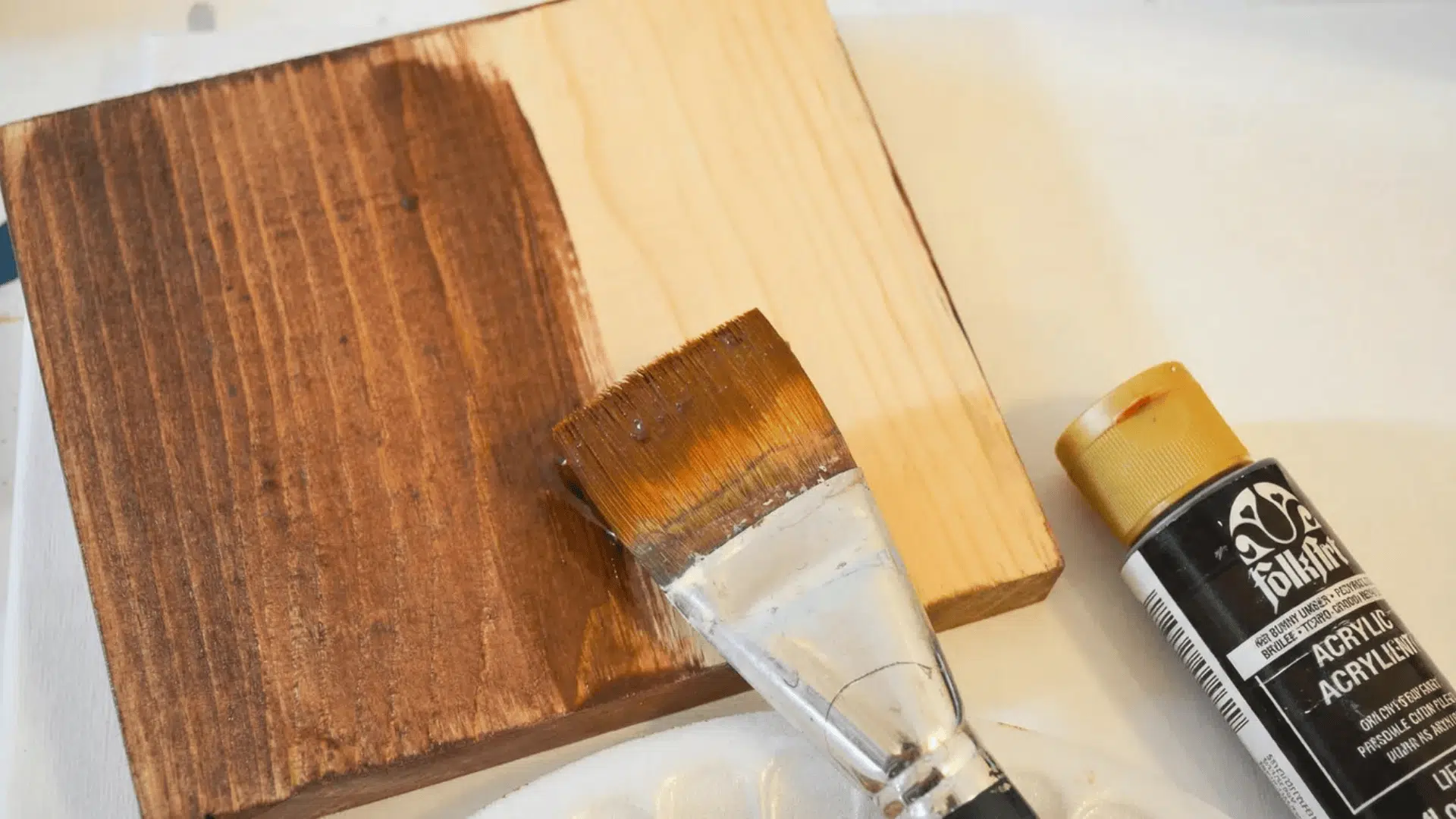 A wooden board half-painted with brown acrylic paint