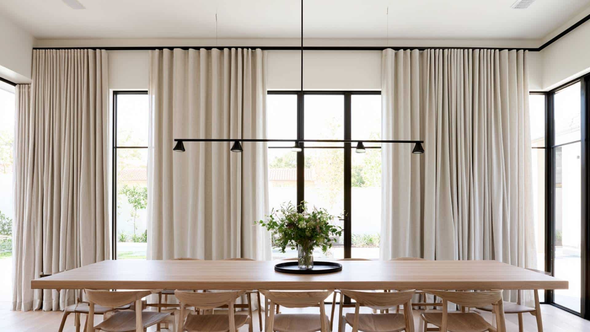 Cream box pleat curtains in a minimalist dining room with black pendant light and wooden table