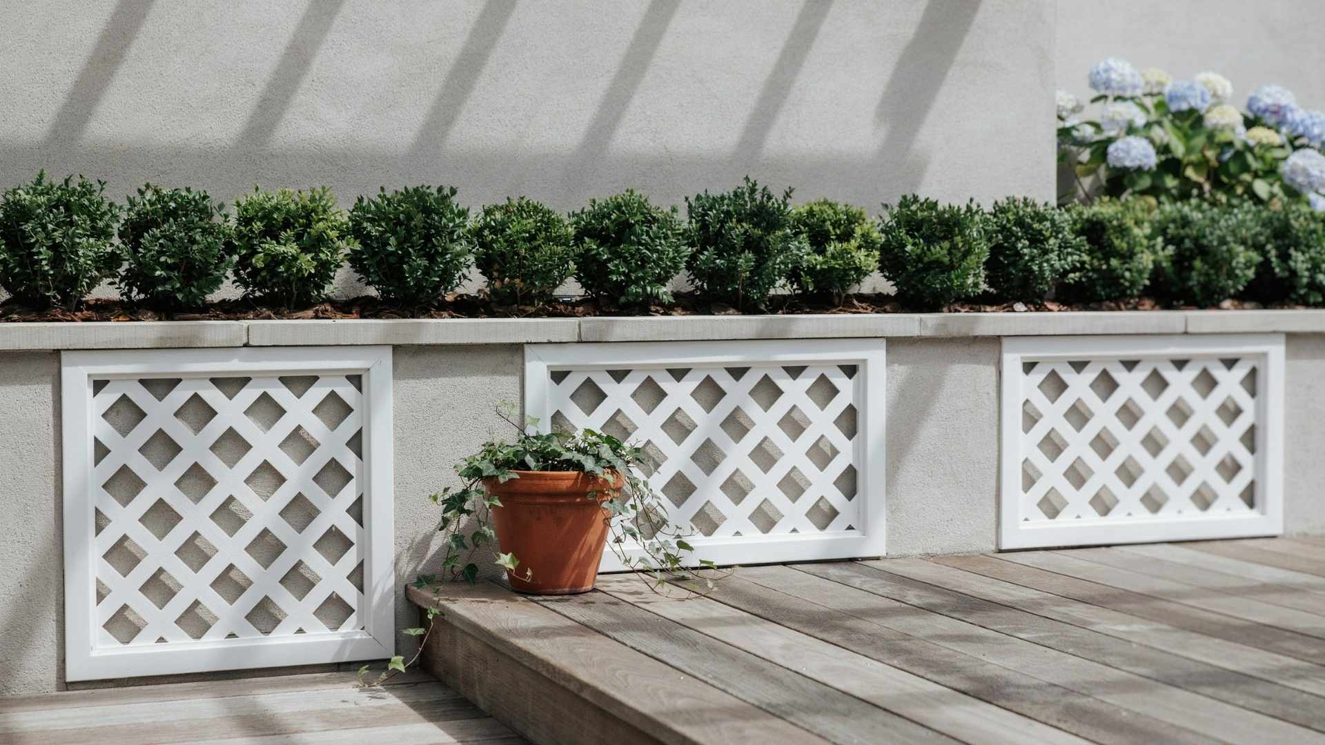 White framed diamond lattice skirting panels installed along a wood deck wall