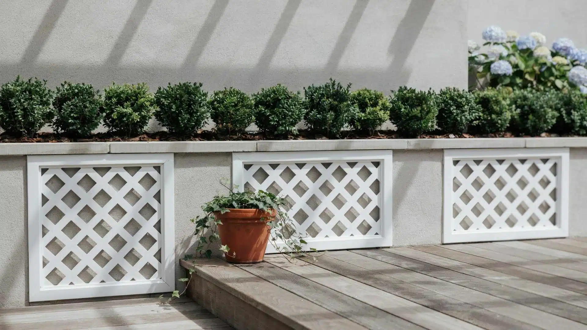 White framed diamond lattice skirting panels installed along a wood deck wall