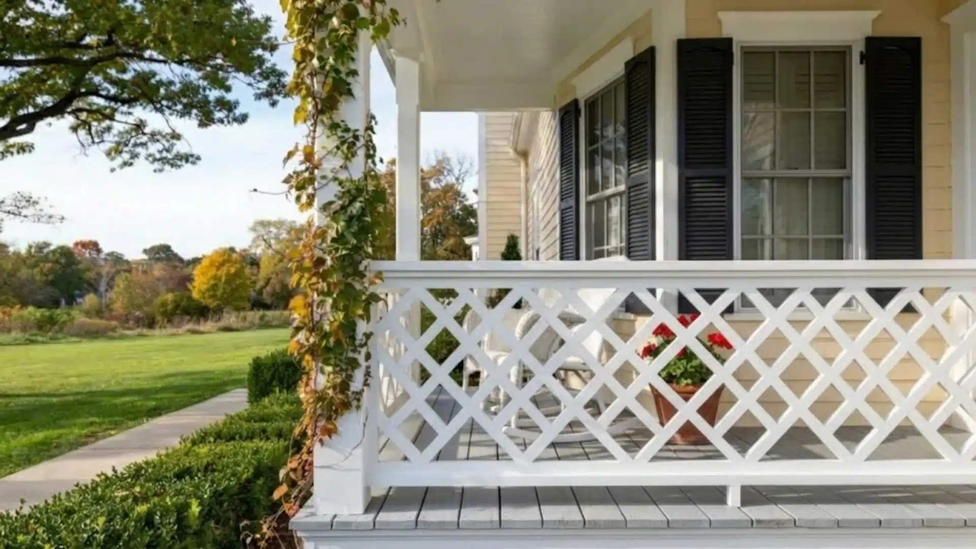 White wood porch railing with a diamond lattice pattern and a climbing vine on the post.