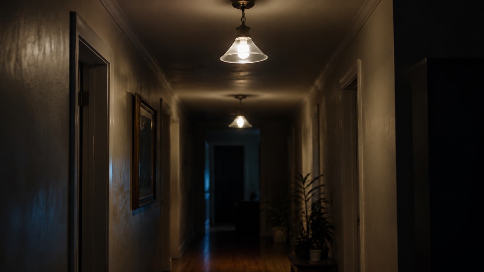 Dimly lit hallway with flickering ceiling lights casting uneven glow over empty corridor interior