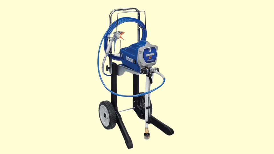 Graco Magnum X7 cart-mounted airless paint sprayer with hose and spray gun on wheeled stand against a light background.