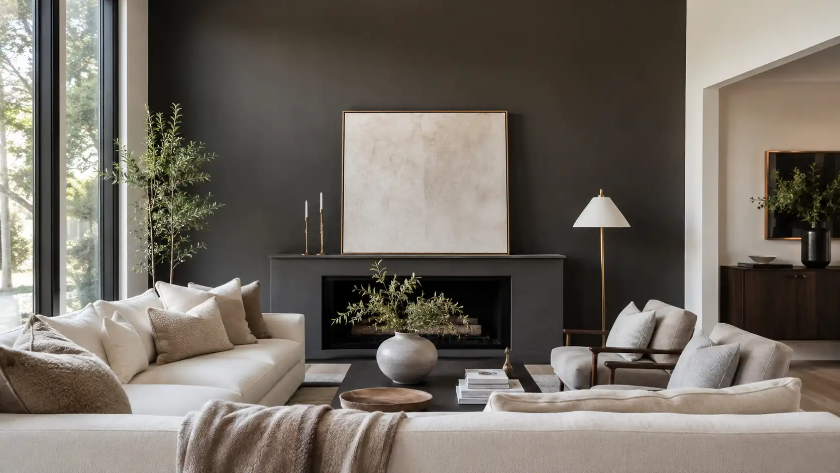 Modern living room with deep espresso-charcoal accent wall, cream sofas, warm neutral textiles, fireplace, and natural daylight.
