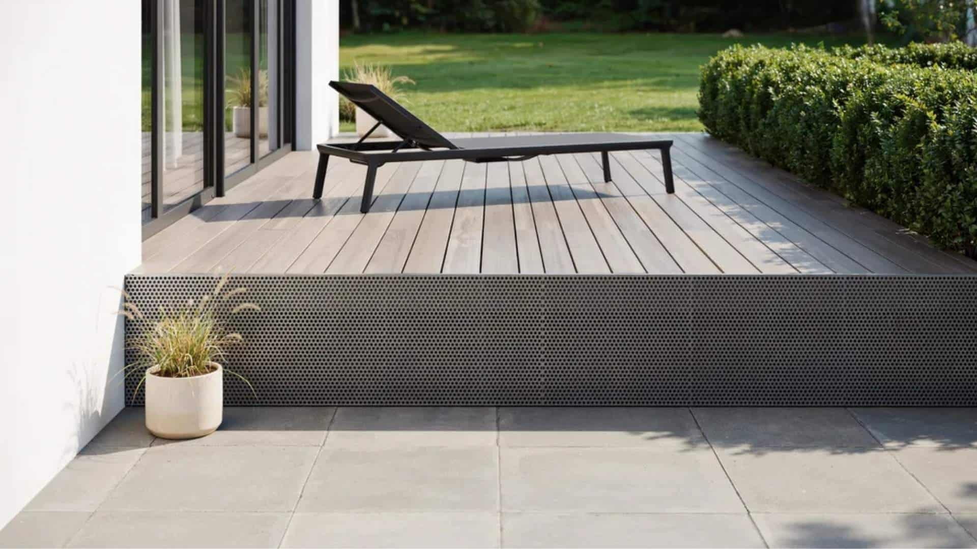 Dark perforated metal deck skirting panel beneath a wood deck with patio below.