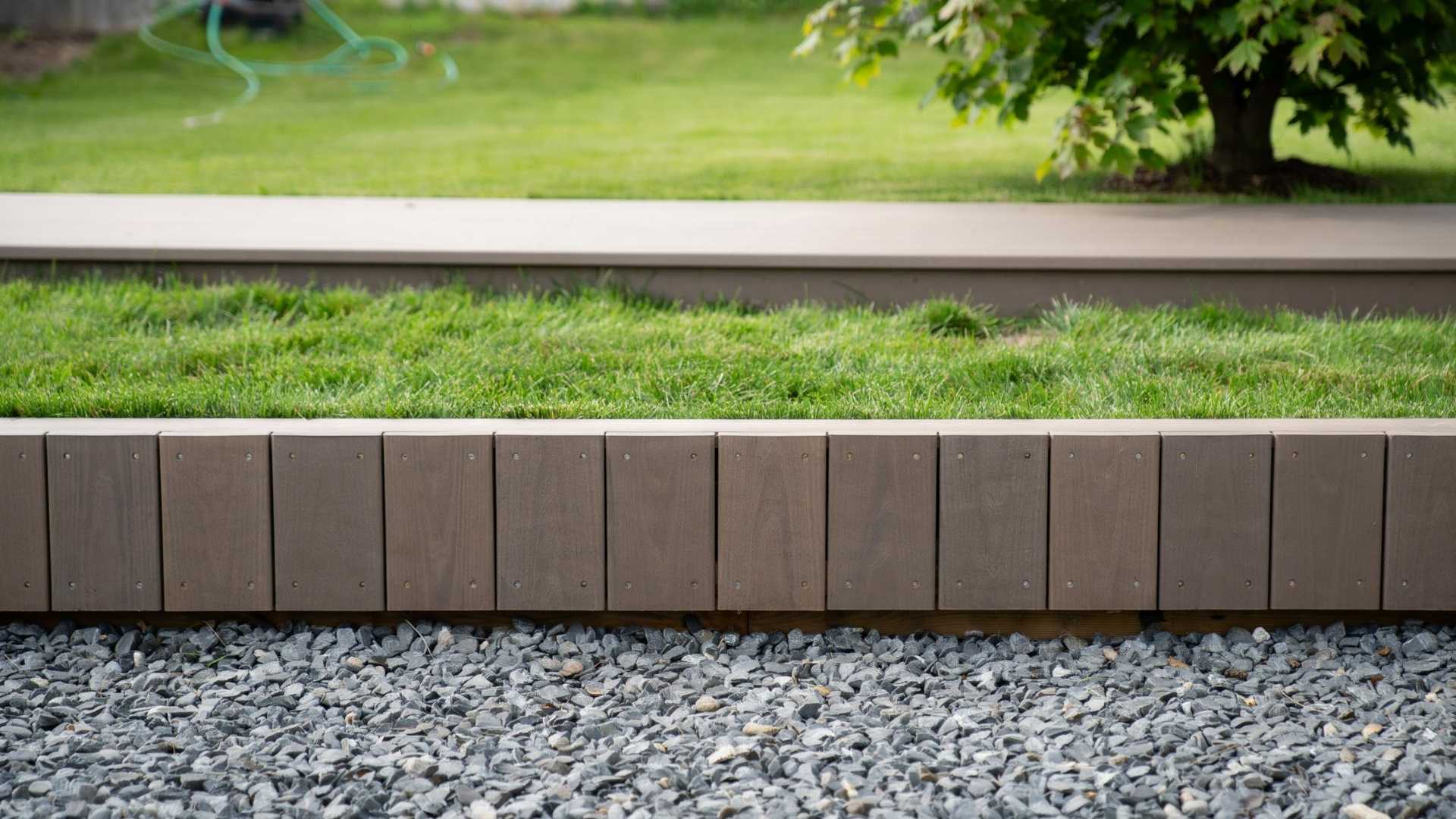 Vertical wood plank skirting sits above gravel, leaving a gap for ventilation underneath.