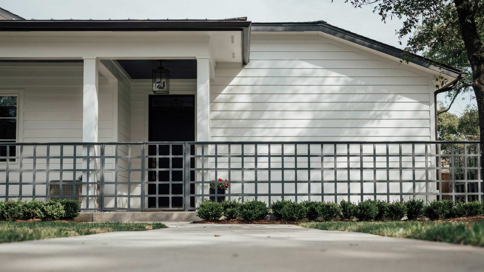 Square grid metal lattice skirting on a white house exterior with front yard landscaping
