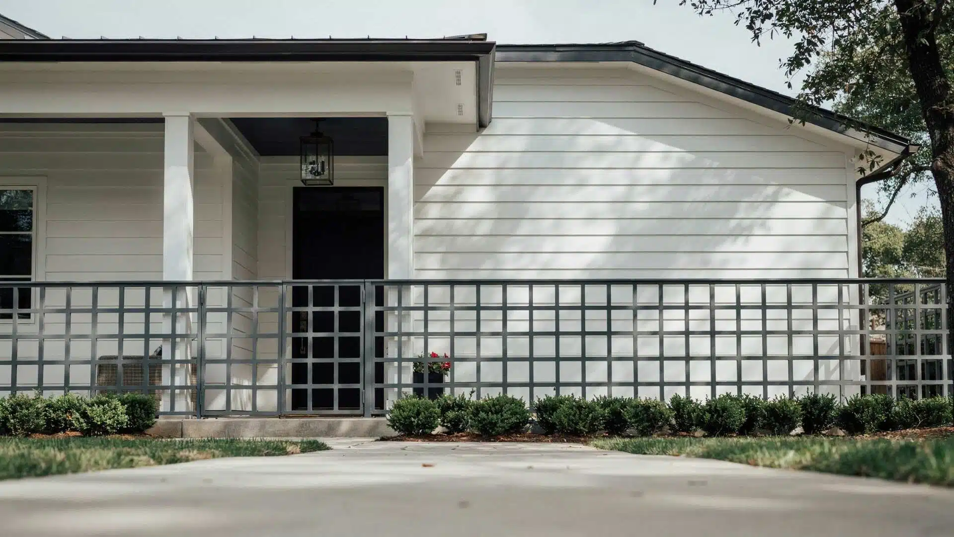 Square grid metal lattice skirting on a white house exterior with front yard landscaping